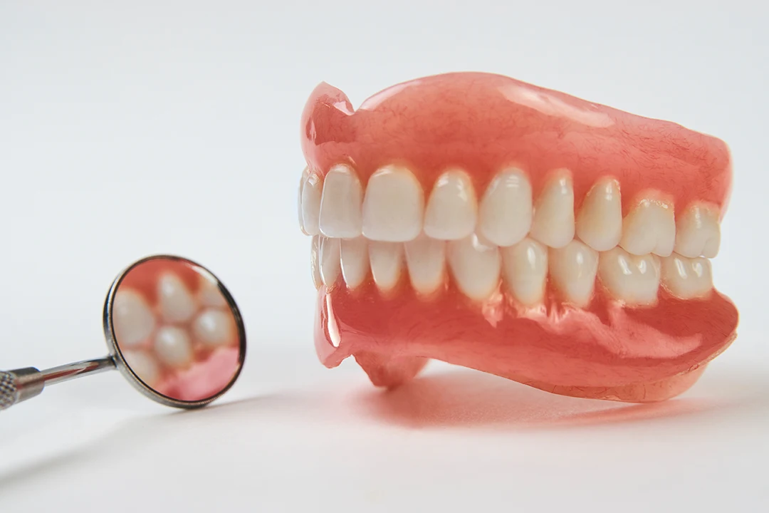 Dentures Sitting on White Surface Spotlighted